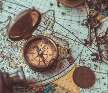 Auf einer antiken Weltkarte liegen ein alter Kompass und ein Fernglas