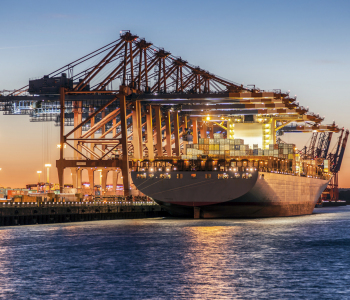 Ein Containerschiff wird im Hamburger Hafen in der Abendsonne beladen