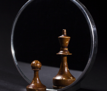 Schachfigur Bauer sieht einen König im Spiegel.