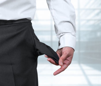 Ein Business-Mann zeigt seine leeren Hosentaschen als Zeichen für die Insolvenz