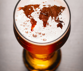 Ein Bierglas, in dessen Schaum die Umrisse einer Weltkarte zu erkennen sind