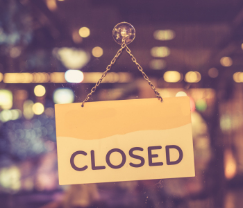 Ein geschlossenes Geschäft mit einem Schild im Schaufenster, auf dem „Closed“ steht 