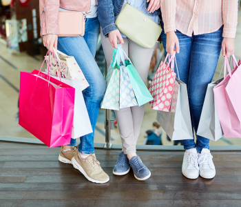 Drei junge Frauen in der Ansicht Bau abwärts in einem Shoppingcenter mit vielen Shoppingtaschen