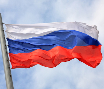 Russische Flagge weht an einem Flaggenmast im Wind vor einem wolkigen Himmel. 