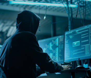 Hacker sitzt vorm Computer mit Kapuzenpulli.