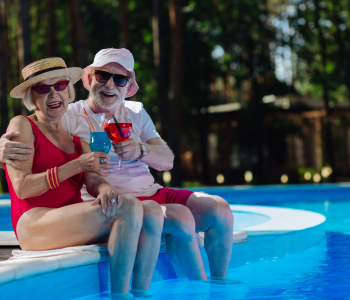Älteres Paar sitzt vergnügt am Pool.