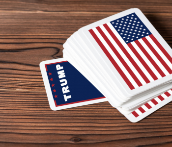 Aus einem Kartendeck mit US-Flaggen-Design ragt eine einzelne Spielkarte, auf der Trump steht
