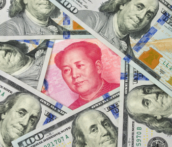 Zahlreiche 100-Dollar-Noten umkreisen einen chinesischen Geldschein 